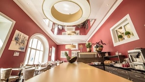 A spacious dining area with high ceilings, large windows, and a central island with a pineapple centerpiece. - Hotel Jakob Regensburg DownTown, BW Signature Collection (Regensburg)