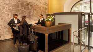 A reception desk with a map on the wall, a large potted plant, and a modern elevator. - Hotel Jakob Regensburg DownTown, BW Signature Collection (Regensburg)