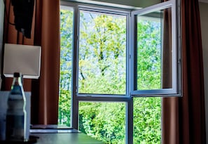 Una habitación con un ventanal, cortinas y una lámpara.
