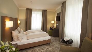 A hotel room with a large bed, a desk, a chair, and a television.