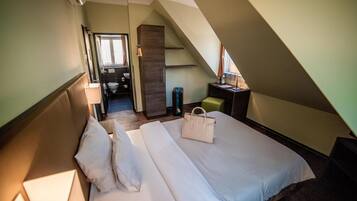 A hotel room with a bed, a desk, a chair, a bathroom, and a staircase.