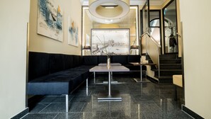 A modern lobby with a black sofa, a reception desk, and a staircase. - Hotel Jakob Regensburg DownTown, BW Signature Collection (Regensburg)
