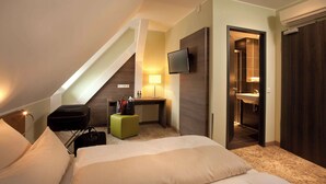 A hotel room with a bed, a desk, a flat-screen TV, a bathroom with a sink, and a staircase. - Hotel Jakob Regensburg DownTown, BW Signature Collection (Regensburg)