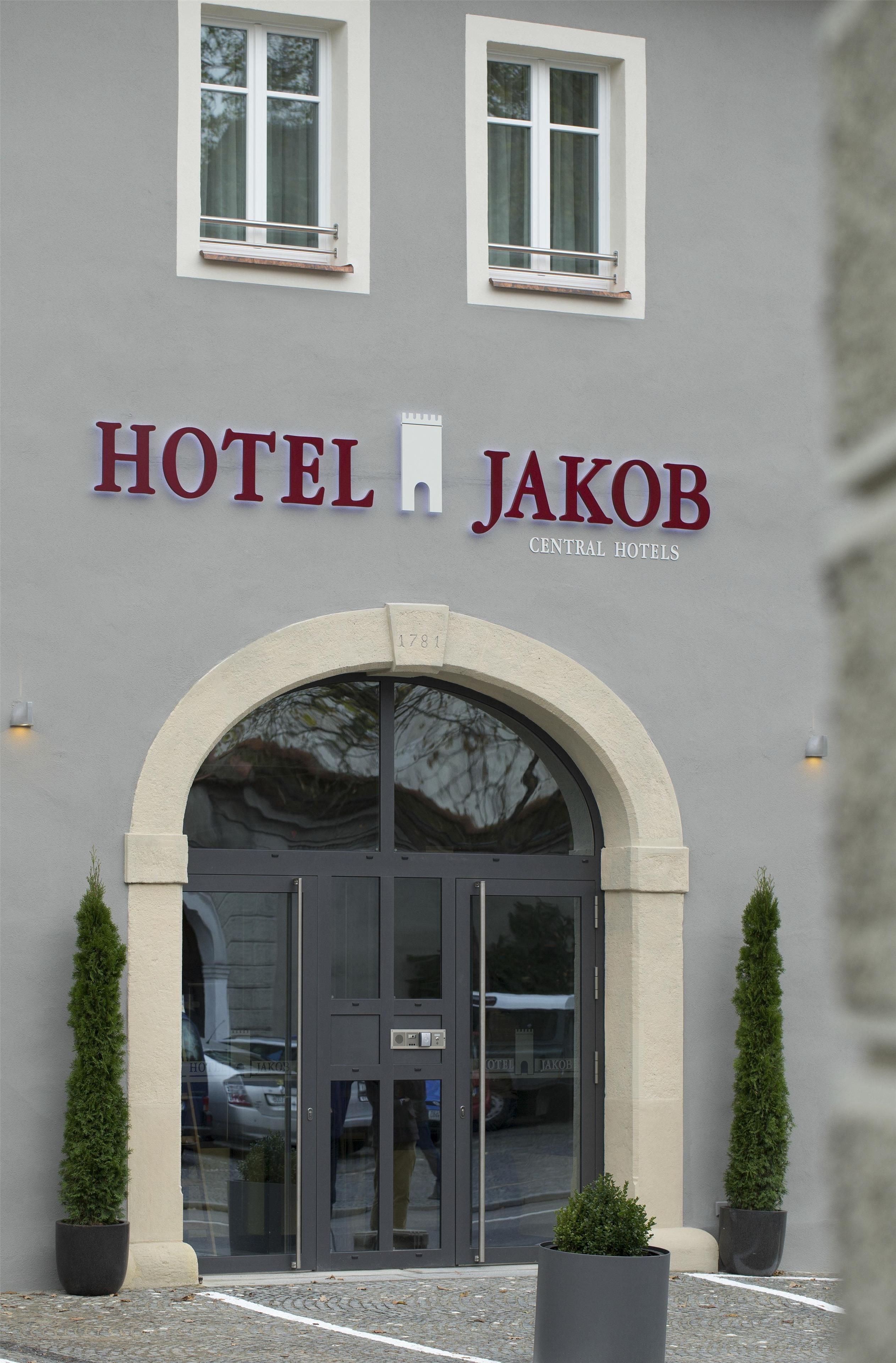 La entrada del Hotel Jakob, con un gran arco, un cartel con el nombre del hotel y dos macetas a cada lado.