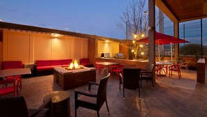 An outdoor patio area with a fire pit, seating, and a bar area. - Homewood Suites by Hilton Queretaro, Mexico (Querétaro)