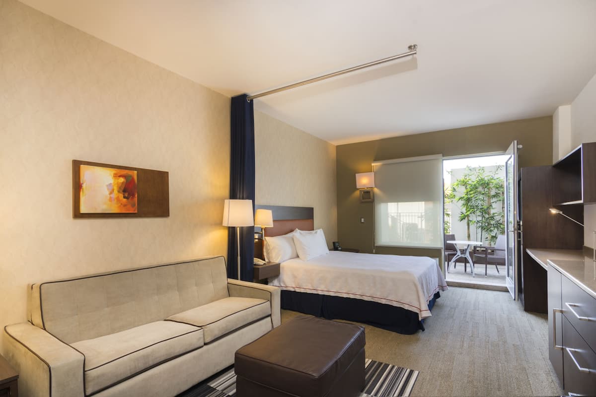 A hotel room with a sofa, a bed, a desk, and a chair.