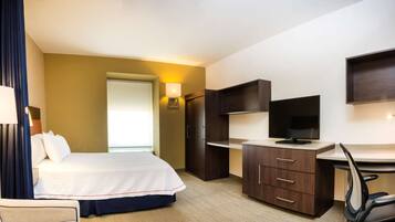 A hotel room with a bed, desk, chair, and a TV.