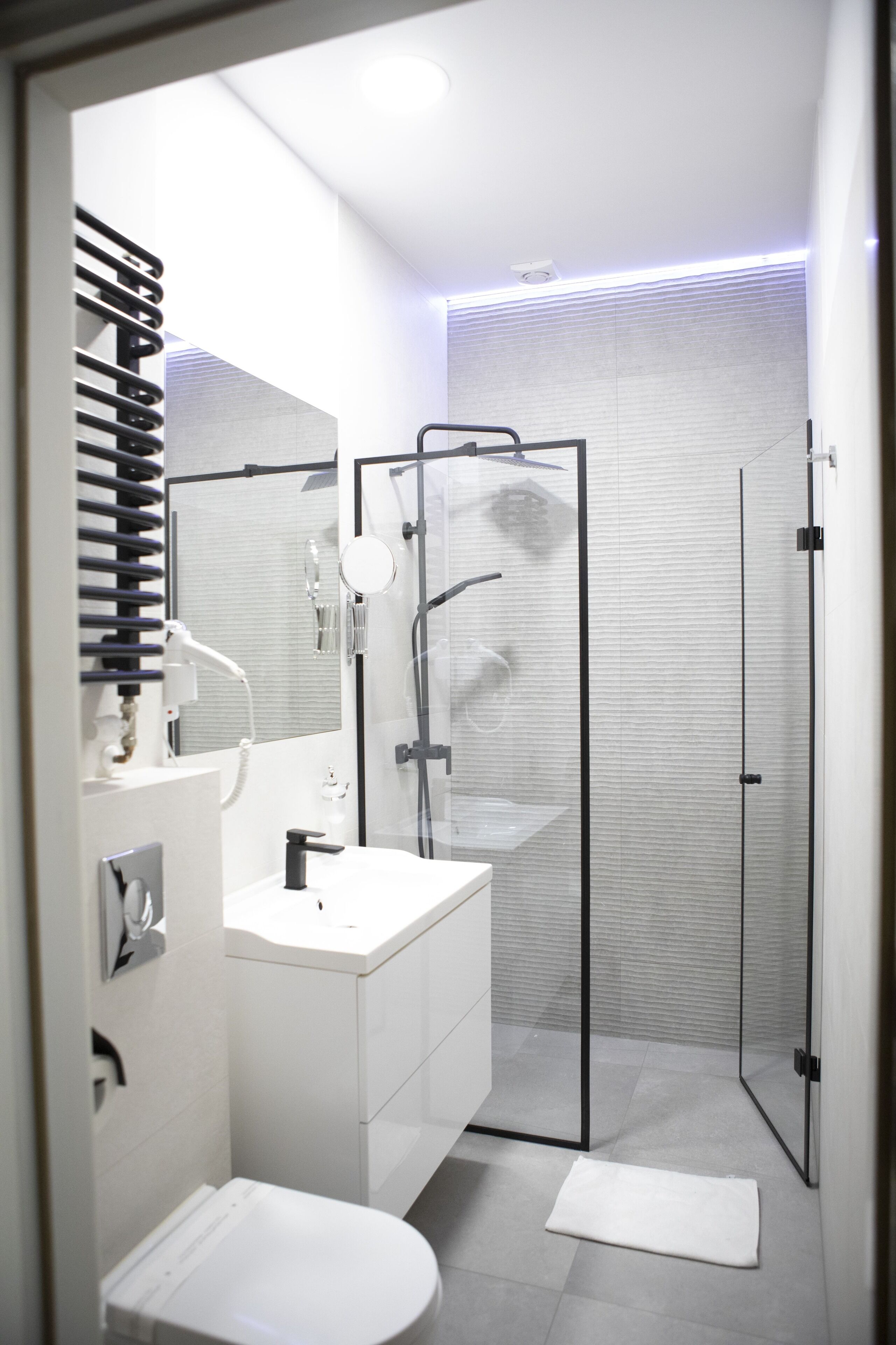 A modern bathroom with a glass-enclosed shower, a white sink, and a large mirror.