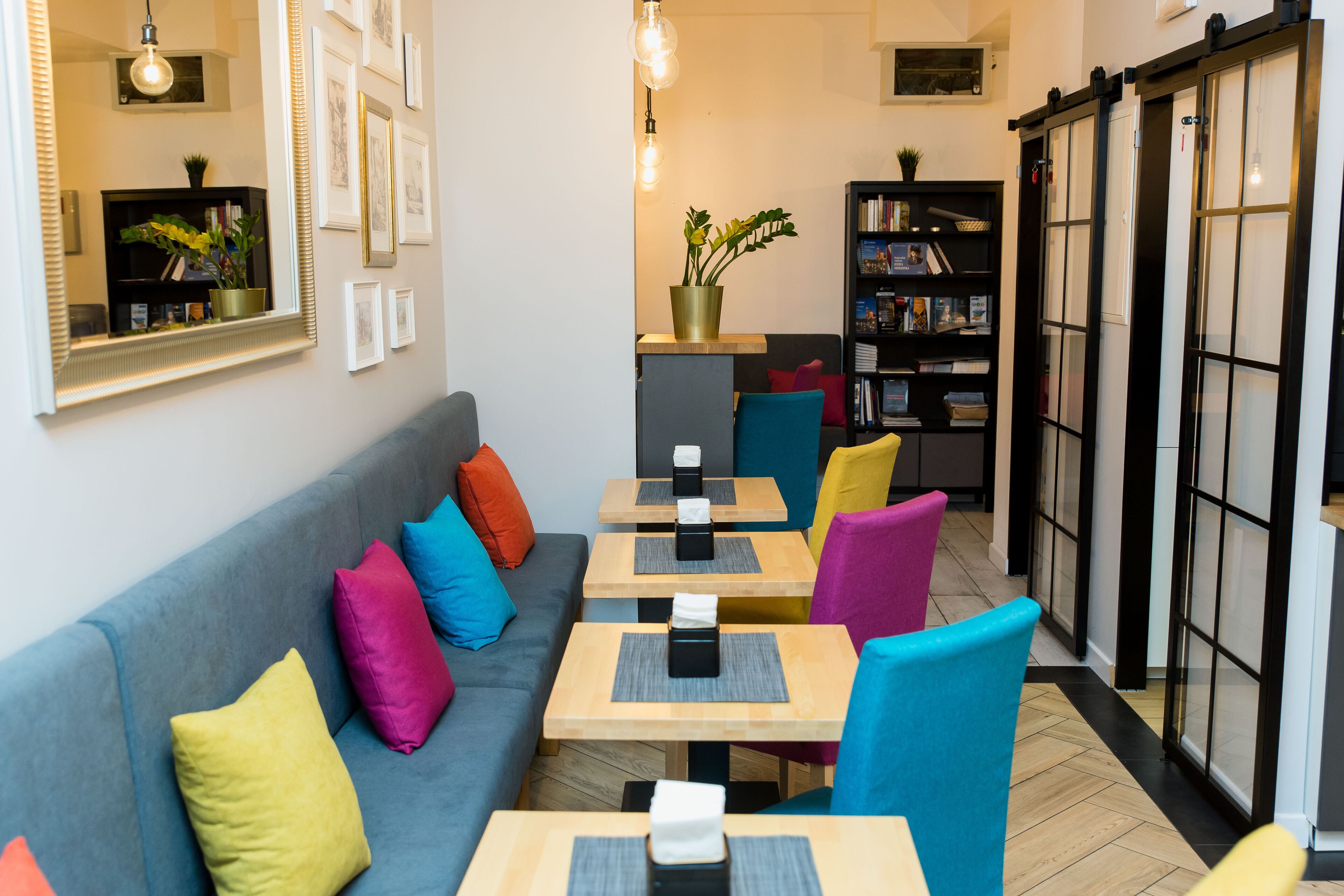 Ein gemütliches Café mit einer Couch, bunten Stühlen und Tischen.