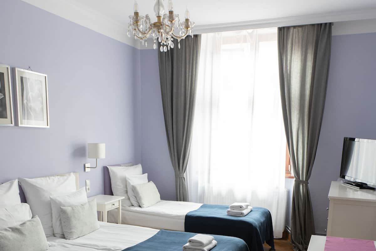 Une chambre d’hôtel avec deux lits, un bureau, une télévision et un lustre.