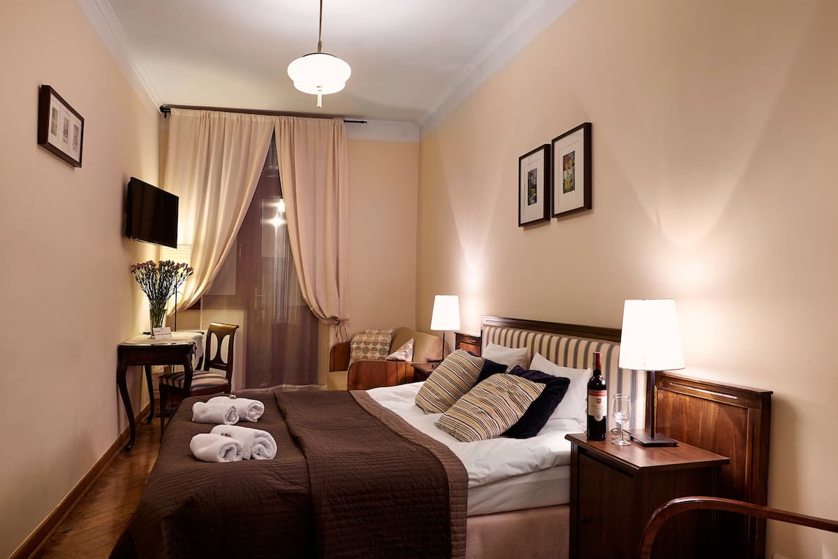 Une chambre d’hôtel avec un lit, des tables de chevet, une télévision et une lampe.