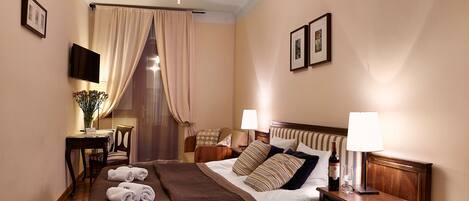 A hotel room with a bed, bedside tables, a TV, and a window with curtains.