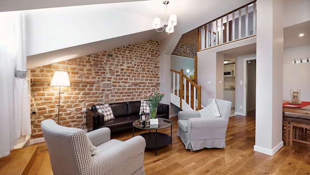 Ein gemütliches Wohnzimmer mit Backsteinwand, einer Holztreppe und einem Essbereich.