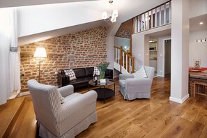 Ein gemütliches Wohnzimmer mit Backsteinwand, einer Holztreppe und einem Essbereich.
