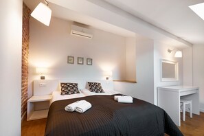 Una habitación de hotel con cama, mesitas de noche, escritorio y espejo.