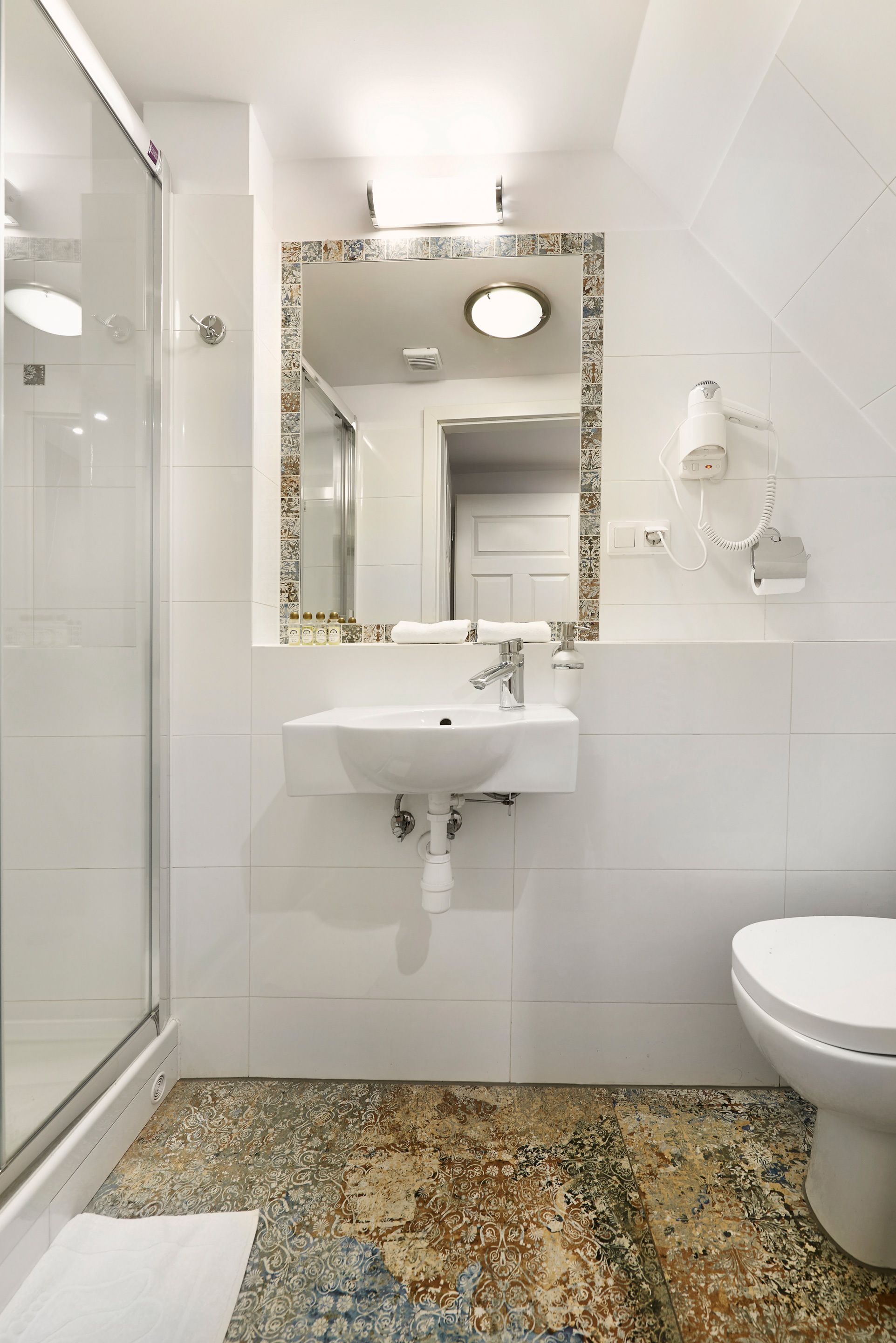 Un baño con cabina de ducha de vidrio, un lavamanos con espejo y un inodoro.