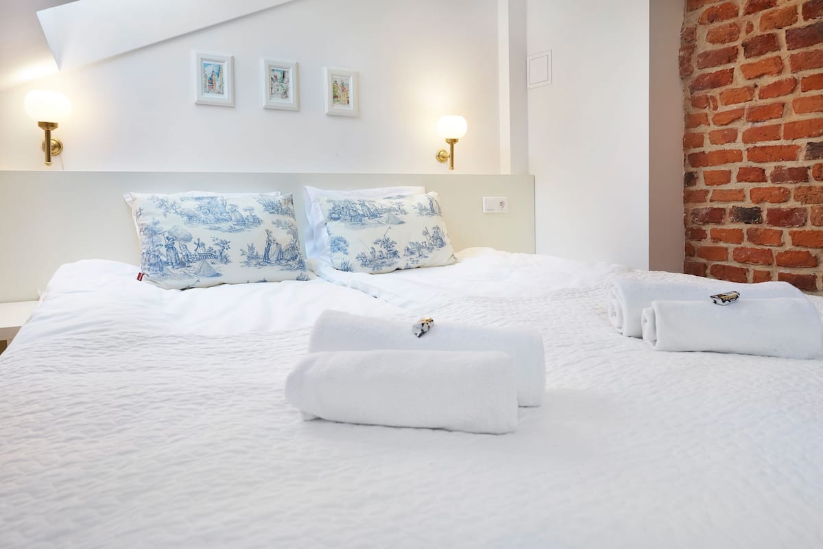 Une chambre d’hôtel avec un grand lit, deux coussins décoratifs et un mur en briques.