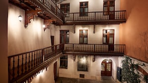 Ein mehrgeschossiges Innenhof mit hölzernen Balkonen und Rundbogenöffnungen.