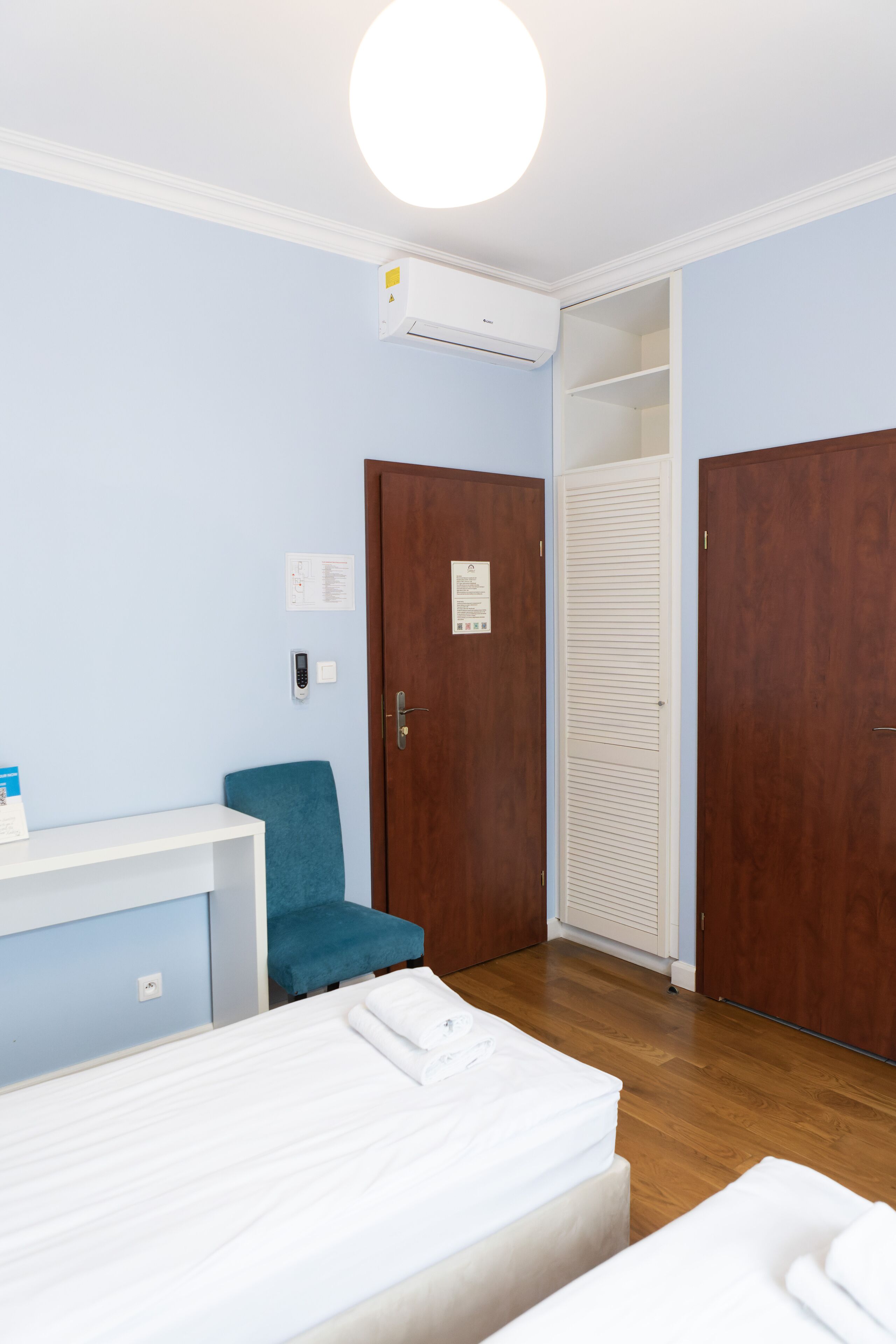 A hotel room with a bed, a desk, a chair, and a wardrobe.