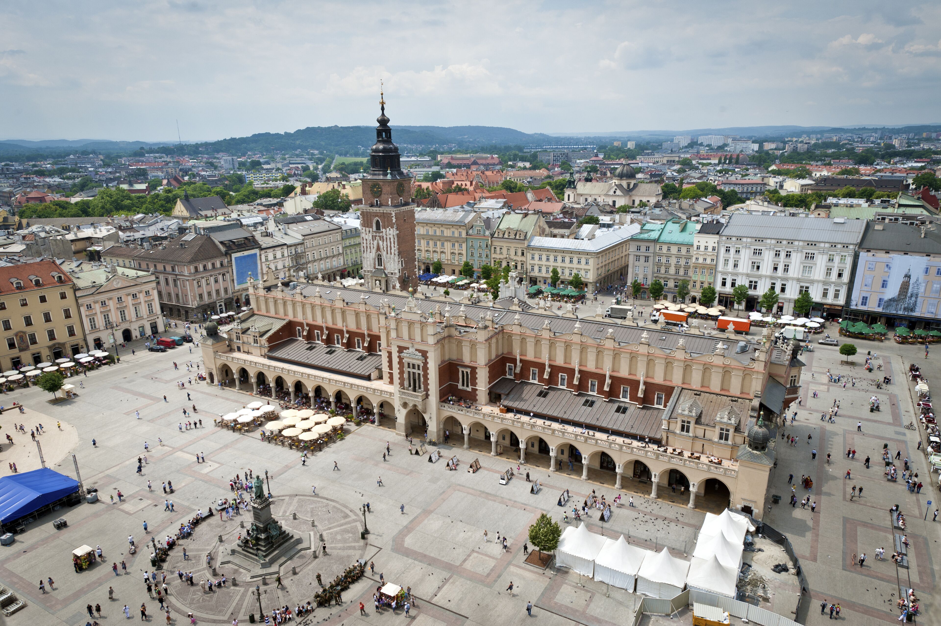 A large public square with historic buildings, a prominent tower, and a central fountain.