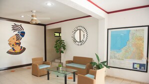 A lobby with wicker furniture, a glass coffee table, a wall map, and a ceiling fan. - Hotel U Xul Kah (Campeche)