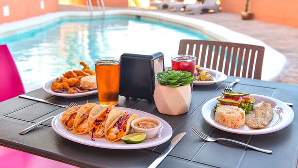 A dining table with plates of food, a drink, and a pool in the background. - Hotel U Xul Kah (Campeche)