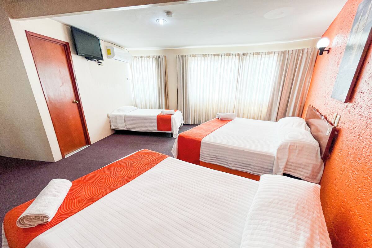 Una habitación de hotel con dos camas, un televisor y una puerta.
