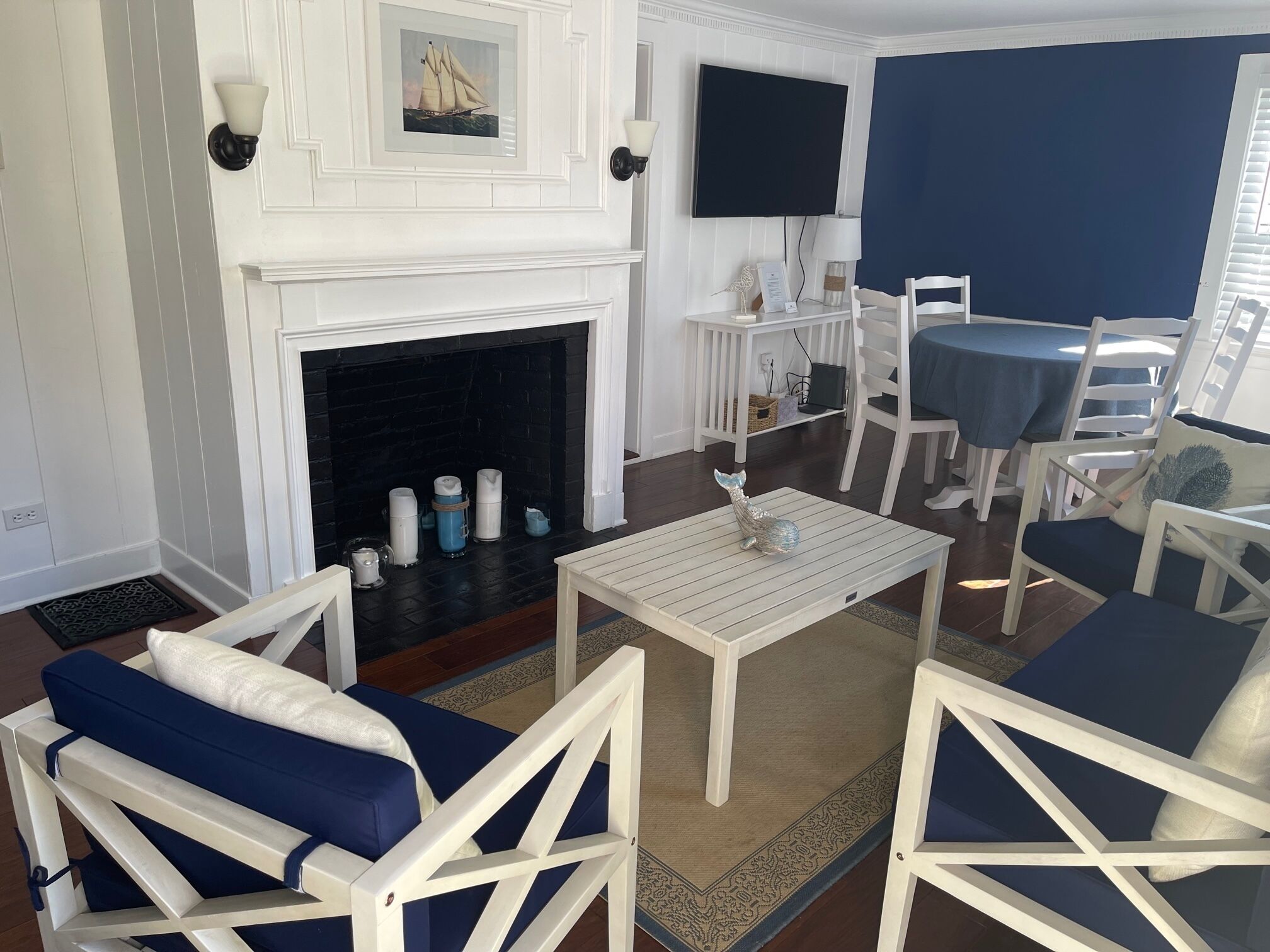 Un salon avec une cheminée, des meubles blancs, un téléviseur et un mur d’accent bleu.