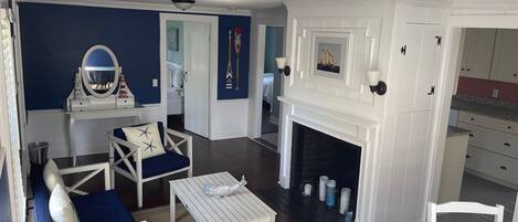 A living room with a fireplace, white furniture, and a blue accent wall.