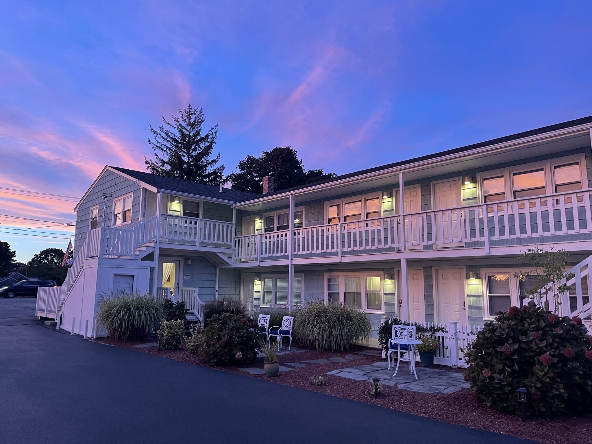 A two-story motel with a balcony on the second floor, a covered front porch, and a parking area in front.