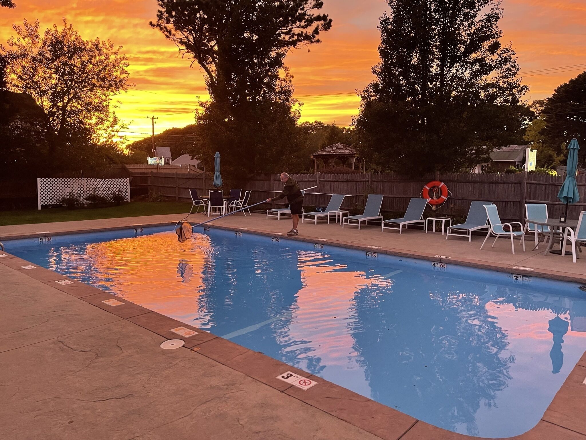 Una piscina con sillas de descanso y un pabellón al fondo.