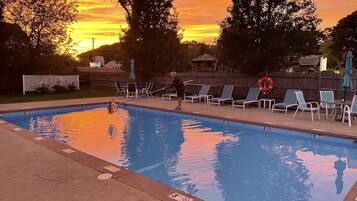 Una piscina con sillas de descanso y un pabellón al fondo.