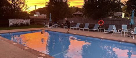 Una piscina con sillas de descanso y un pabellón al fondo.
