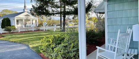 A porch with white rocking chairs and a white fence.