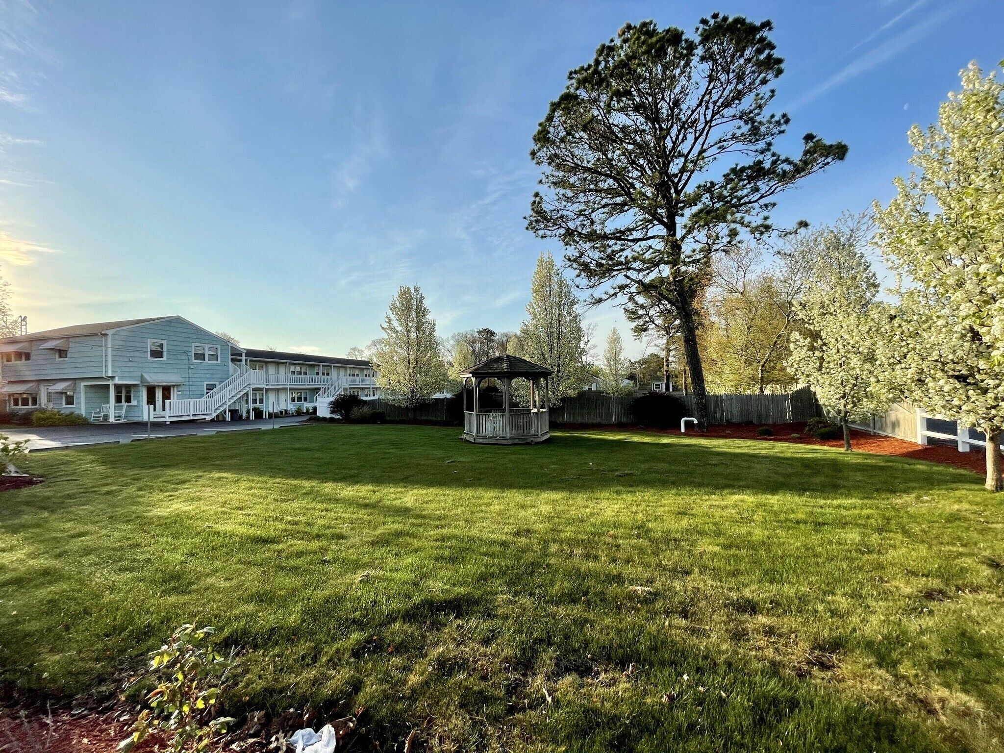 A residential property with a large lawn, a gazebo, and a two-story house with a porch.