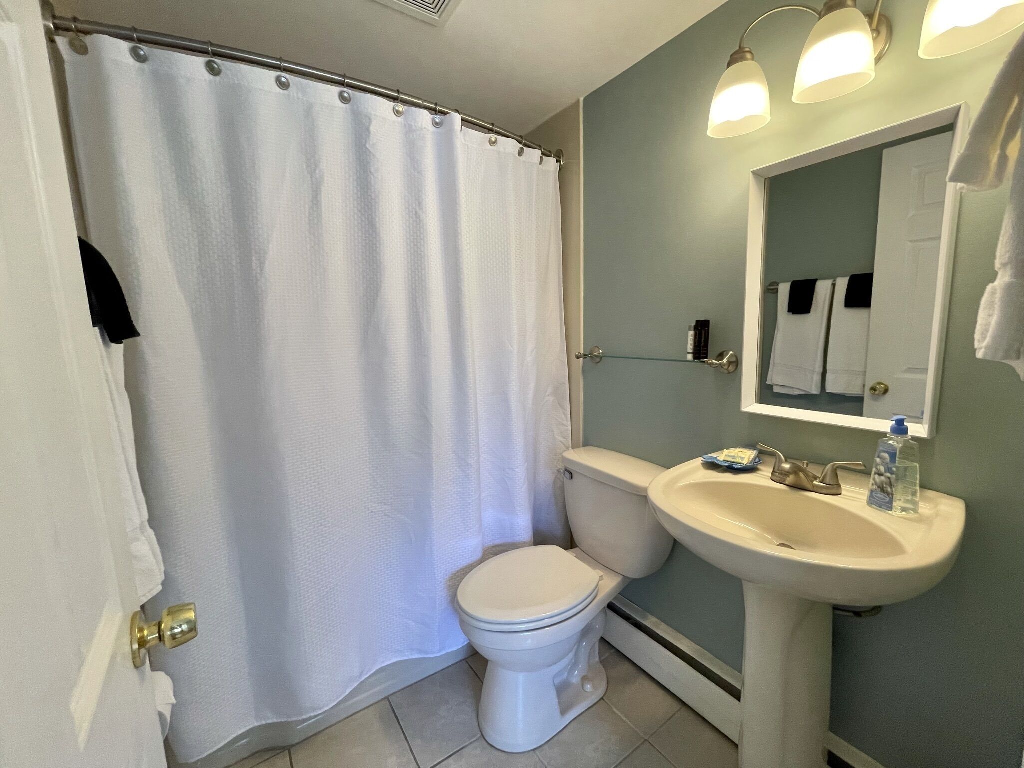 Un bagno con il water bianco, un lavandino e una tenda per la doccia.