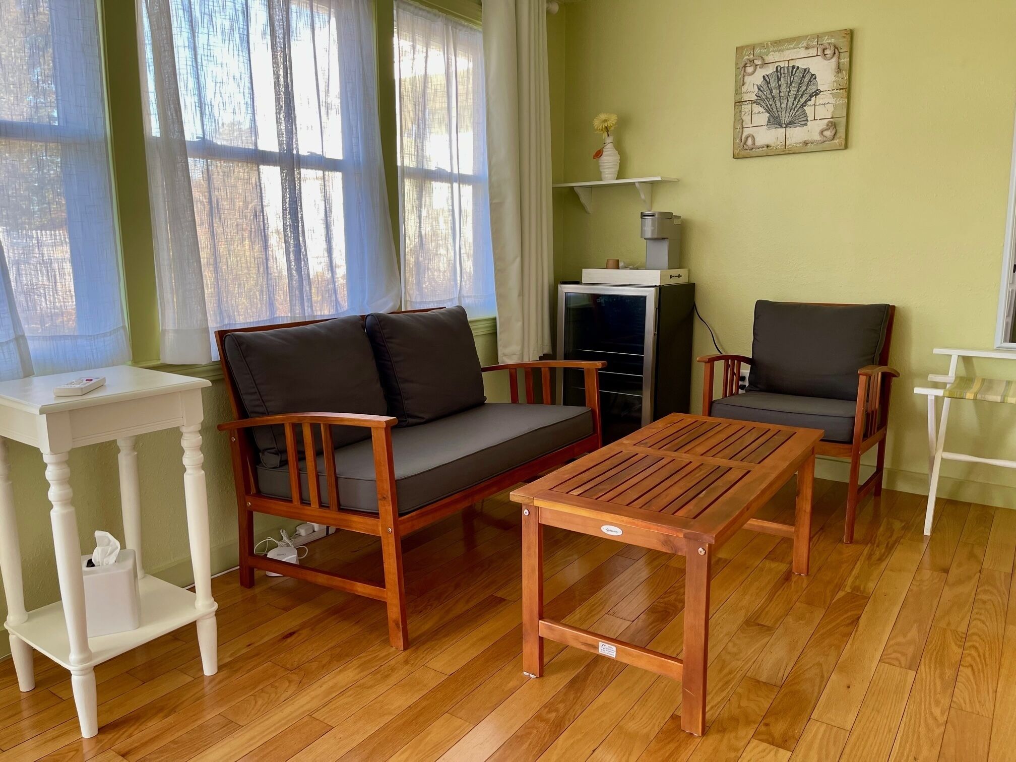 A cozy living room with a wooden sofa, two armchairs, a small table, and a TV stand.