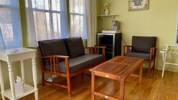 A cozy living room with a wooden sofa, two armchairs, a small table, and a TV stand.