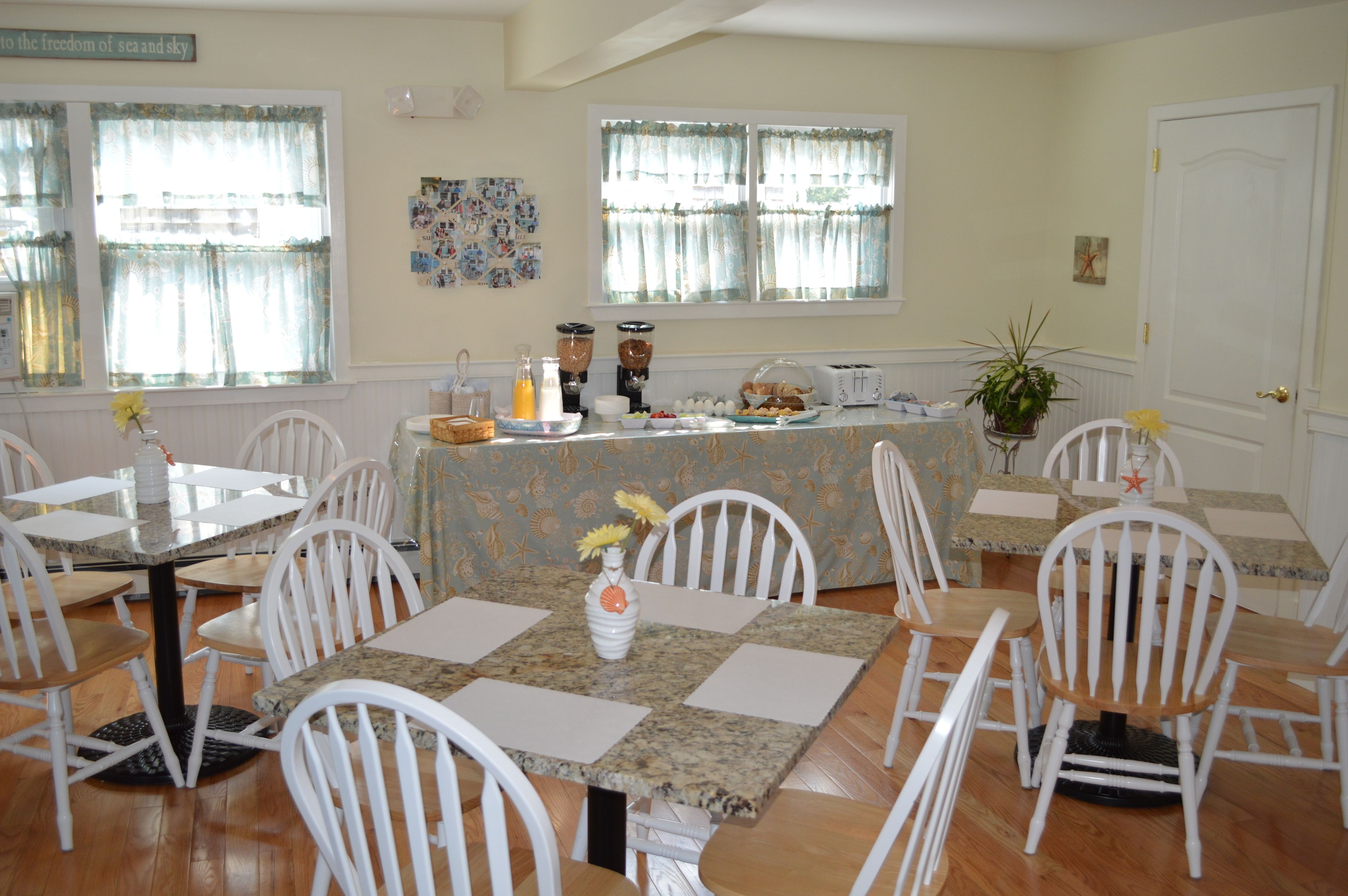 A dining area with a buffet setup, white chairs, and a table with a floral centerpiece.