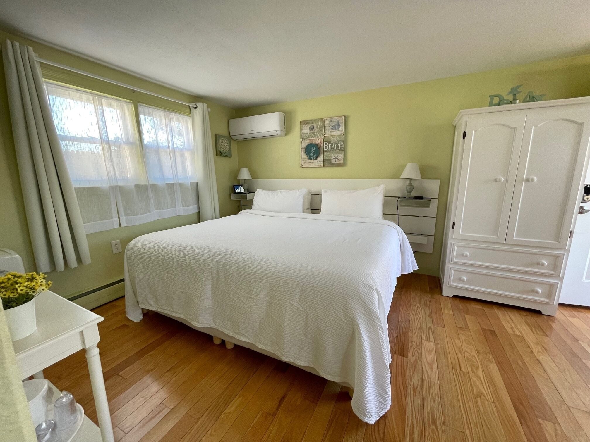 A neatly arranged bedroom with a large bed, bedside tables, a wardrobe, and a window with curtains.