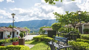 Ein friedlicher Innenhof mit einer Bank, Blumentöpfen und Blick auf ferne Berge.