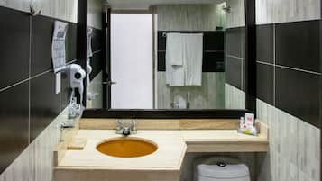 Een moderne badkamer met een beige wastafel, een haardroger bevestigd aan de muur en een toilet.