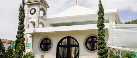 Una iglesia moderna con un campanario, grandes ventanales de arco y una cruz en el techo.