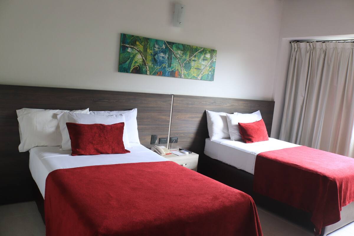 Een hotelkamer met twee bedden, een nachtkastje, een telefoon en een schilderij aan de muur.