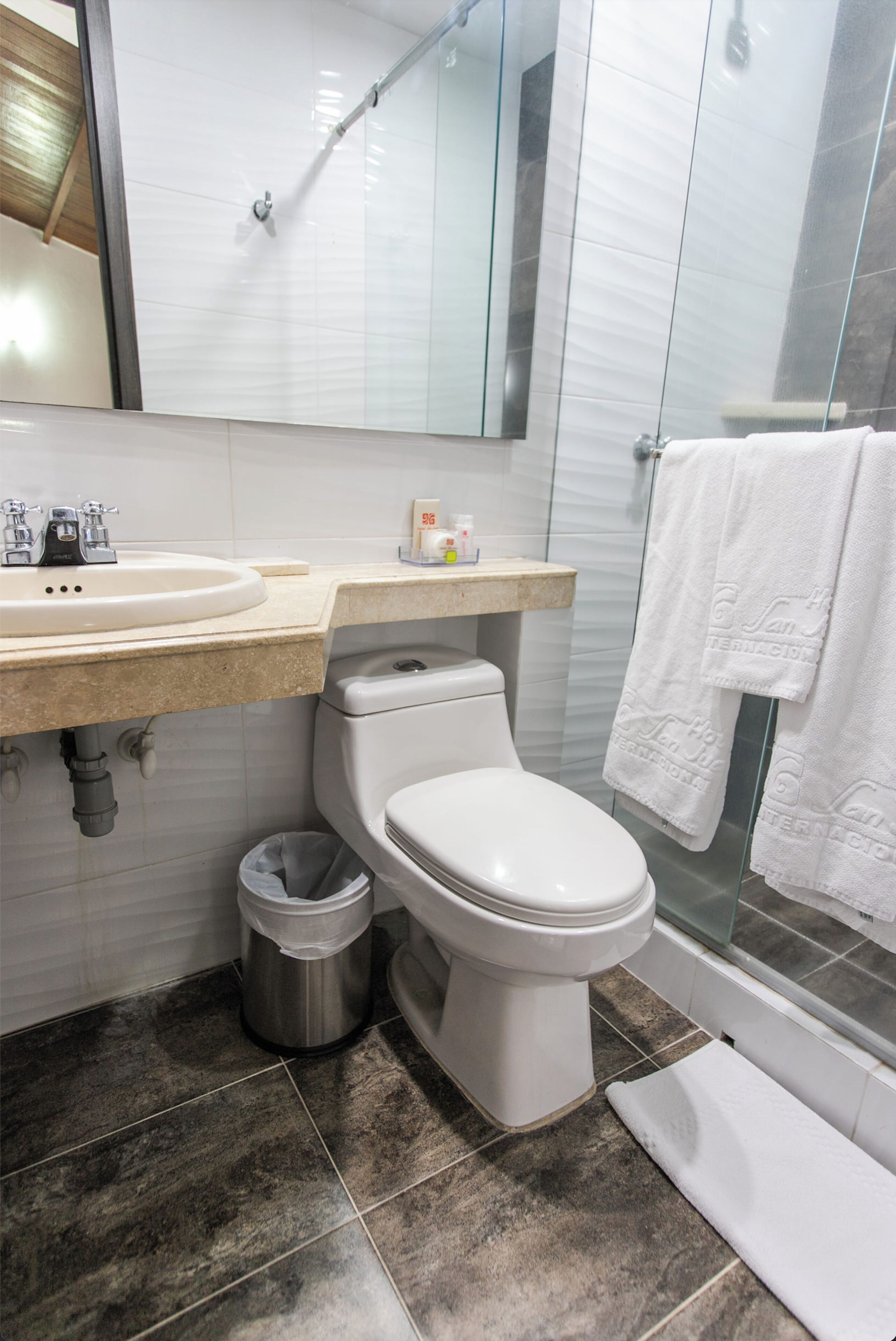A modern bathroom with a white toilet, a sink, and a glass shower enclosure.