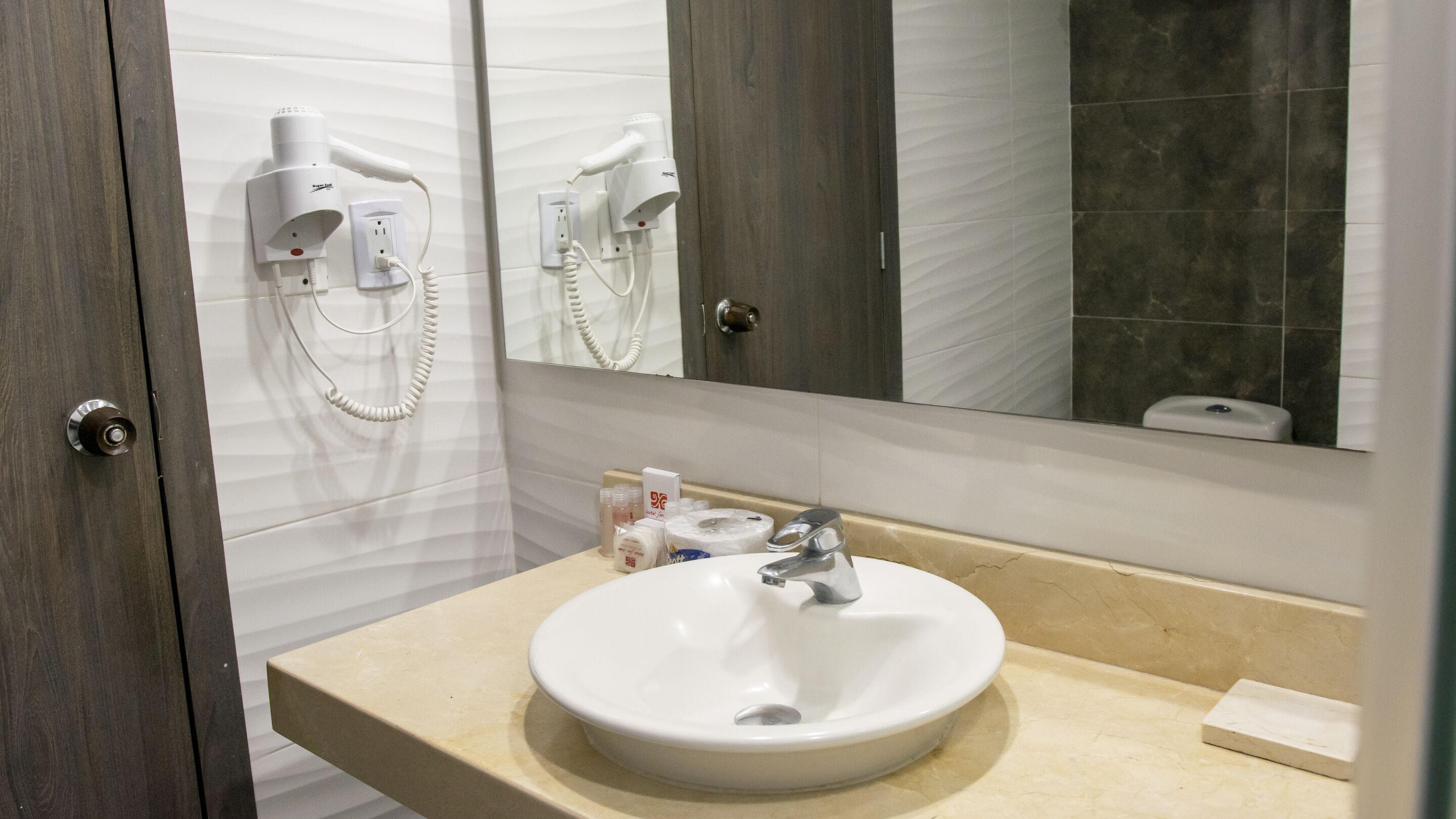 A bathroom with a white sink, a mirror, and hair dryers mounted on the wall.