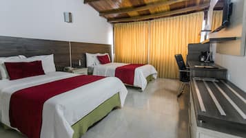 A hotel room with two beds, a desk, a chair, a TV, and a window with curtains.