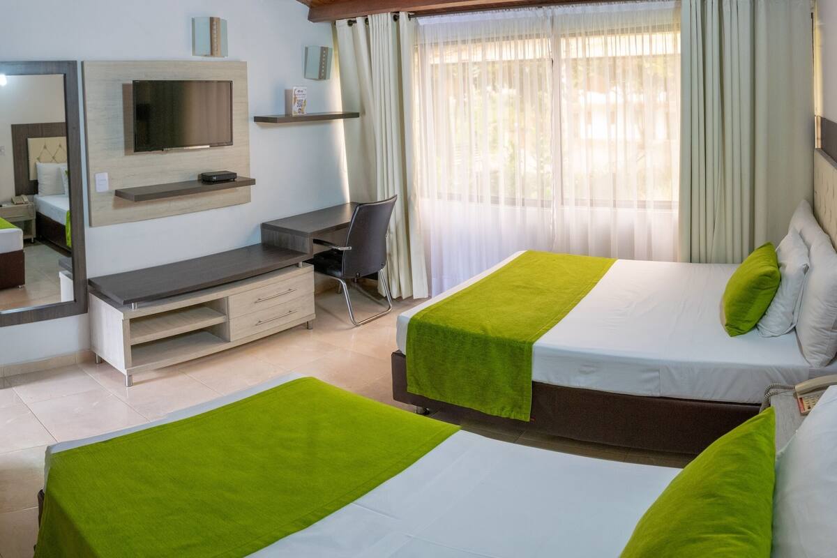Een hotelkamer met twee bedden, een televisie, een bureau en een spiegel.