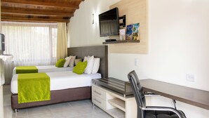 Ein Hotelzimmer mit Bett, Schreibtisch, Stuhl, Fernseher und Bücherregal.