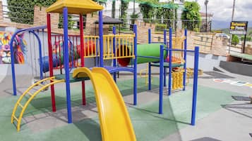 Ein Spielplatz mit Rutsche, Klettergerüsten und einer grünen Tunnelrutsche.